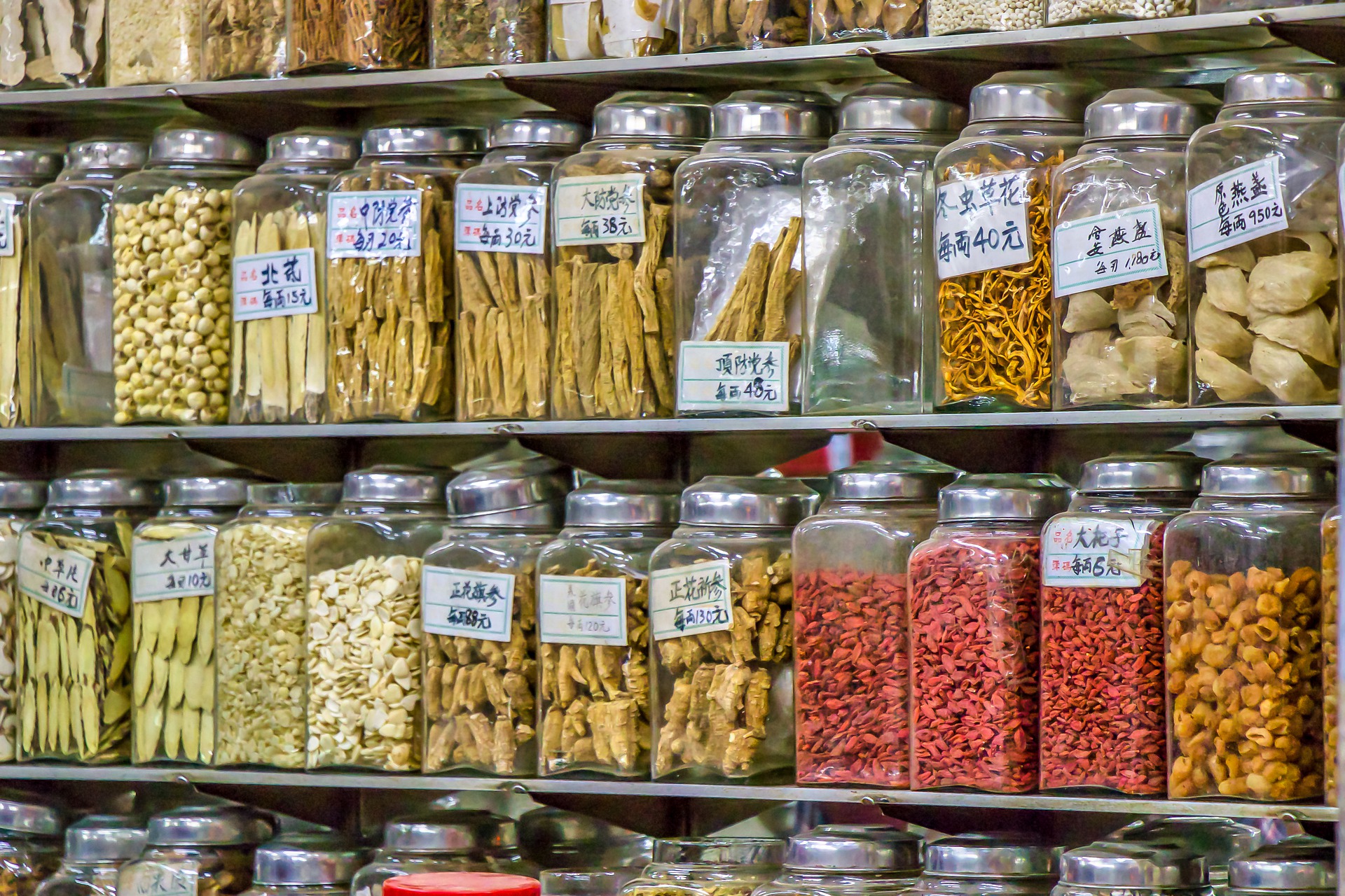 Shelves lined with labeled glass jars containing various dried herbs, roots, and seeds in a traditional Chinese Medicine shop in NE Portland.